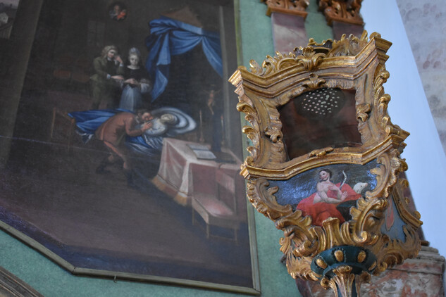 Lucerna a v pozadí detail obrazu s výjevem z legendy sv. Isidora