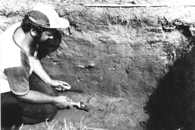 Snímek z průběhu výzkumu v roce 1985. Pracovník začišťuje objev rozměrného fragmentu nádoby z doby bronzové. Zdroj: Muzeum Cheb