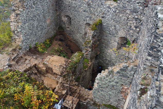 Celkový pohled na provedené archeologické práce. V popředí odhalený interiér s hliněnou omítkou a zaniklým dveřním otvorem, v pozadí pozůstatky trasy přístupového schodiště a pozdně středověké požářiště. | © Autor F. Prekop