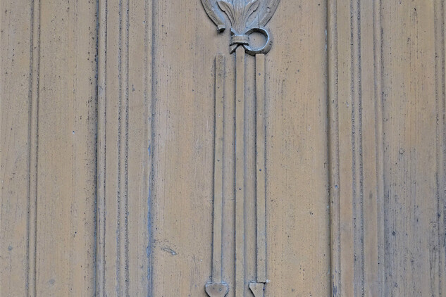 Detail dveří – reliéfní řezba vavřínového věnce se závěsy 