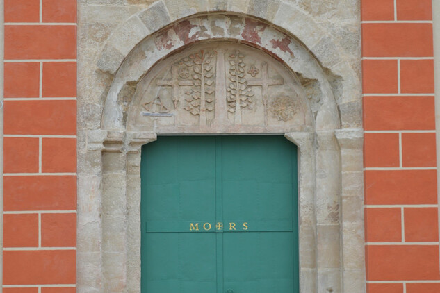 Hlavní vstup do kostela s obnoveným románským portálem, pozůstatkem středověké stavební etapy objektu.